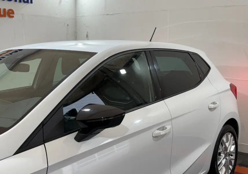 Vue latérale gauche d'une SEAT Ibiza blanche 2024 avec rétroviseur noir et vitres teintées.
