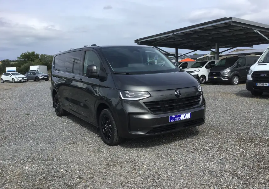 Volkswagen Transporter T7 gris anthracite vu en 3/4 avant droit avec jantes noires et calandre moderne.
