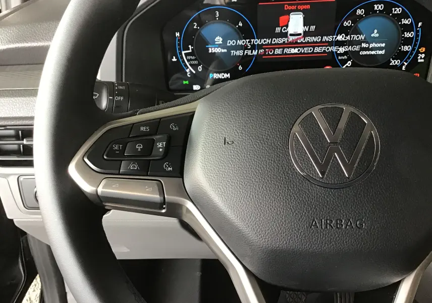 Gros plan sur le volant multifonction et le tableau de bord numérique du Volkswagen Transporter T7 gris anthracite 2025.