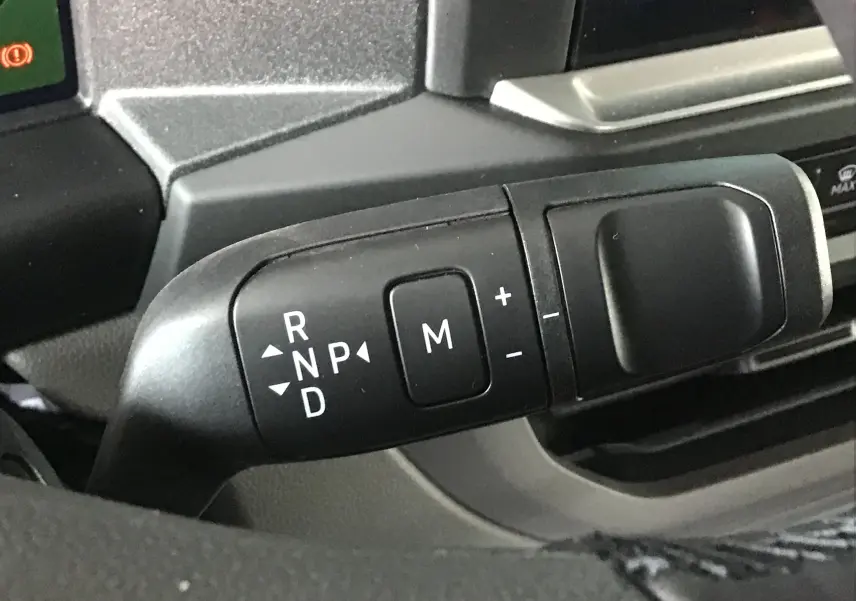 Le levier de boîte automatique avec commandes de mode manuel dans l'habitacle du Volkswagen Transporter gris anthracite.