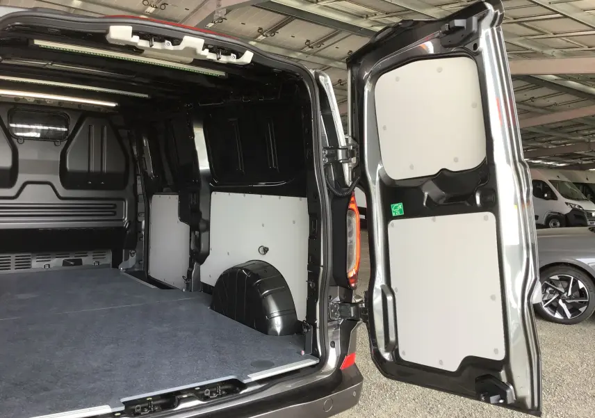 Vue arrière ouverte du Volkswagen Transporter T7 gris anthracite, montrant l'espace de chargement et la porte battante droite.