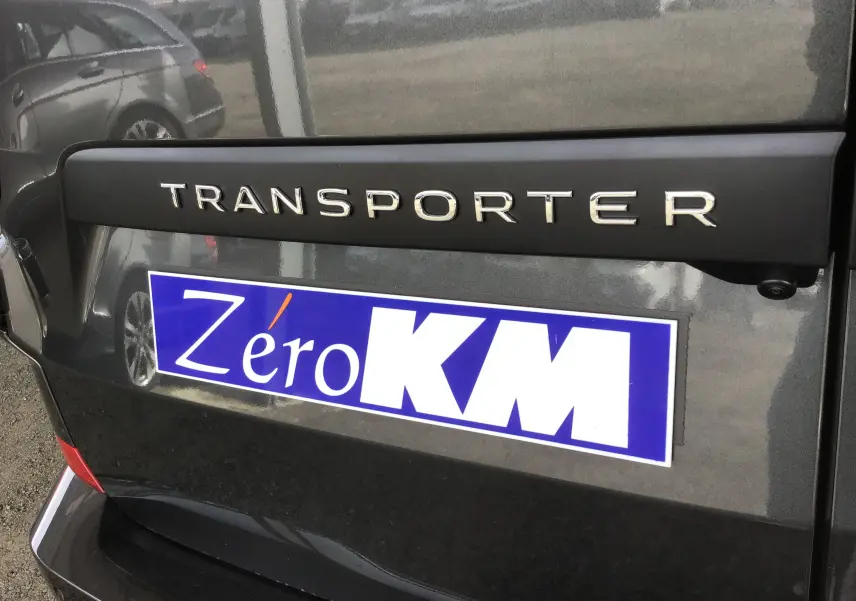 Gros plan sur l'arrière gris anthracite du Volkswagen Transporter avec logo et plaque Zéro KM visible.