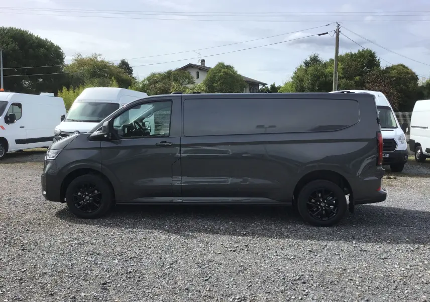Vue de profil côté gauche d'un Volkswagen Transporter T7 gris anthracite avec jantes noires et barres de toit repliables.