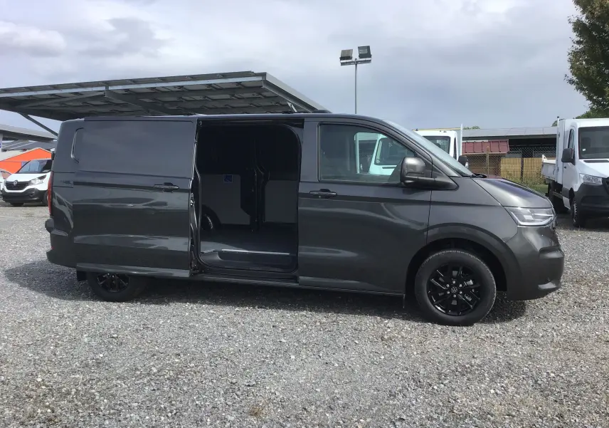 Vue de profil côté droit d'un Volkswagen Transporter T7 gris anthracite avec porte coulissante ouverte et jantes noires.
