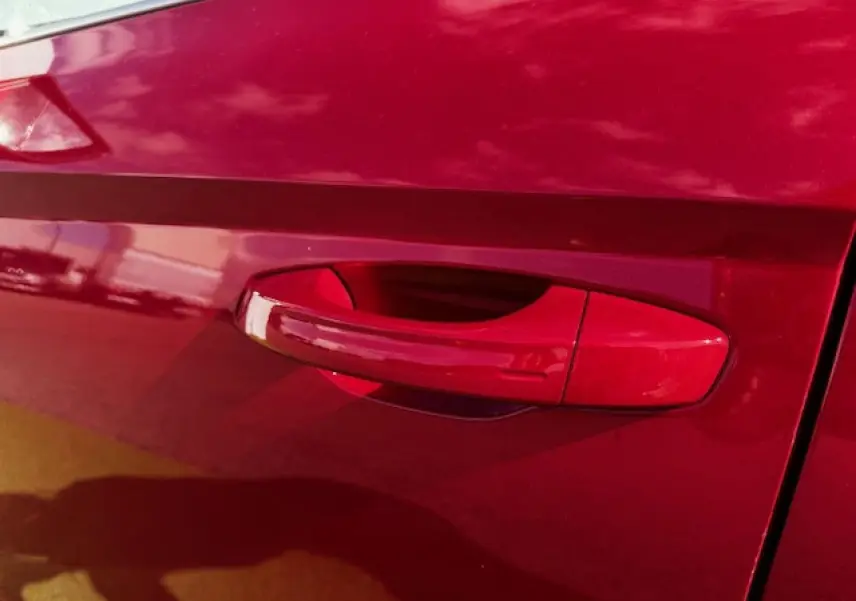 Poignée de porte rouge vif côté gauche d'une SEAT ARONA 2024 avec peinture Rouge Désir et toit noir.