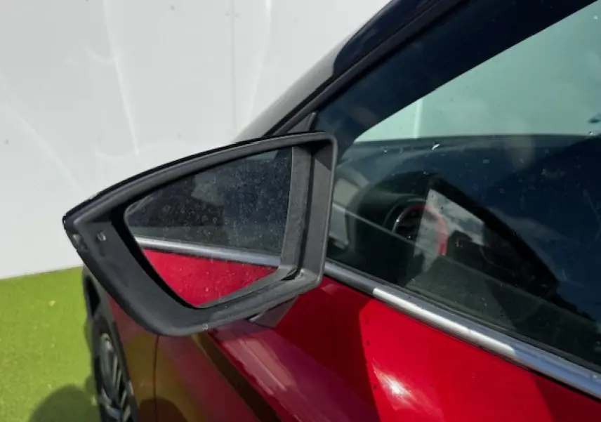 Gros plan sur le rétroviseur côté gauche du SEAT Arona 2024 rouge Désir avec toit noir et vitres teintées.