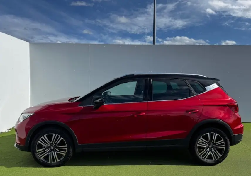 Vue latérale droite d'un SEAT Arona 2024 rouge Désir avec toit noir et jantes alliage noires.