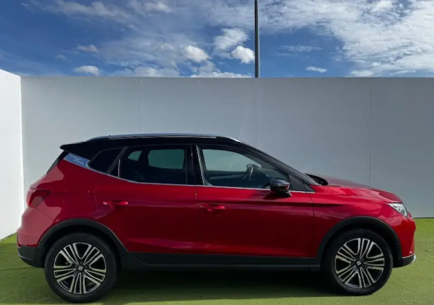 SEAT Arona rouge Désir avec toit noir, vue de profil côté gauche, jantes alliage et vitres teintées.