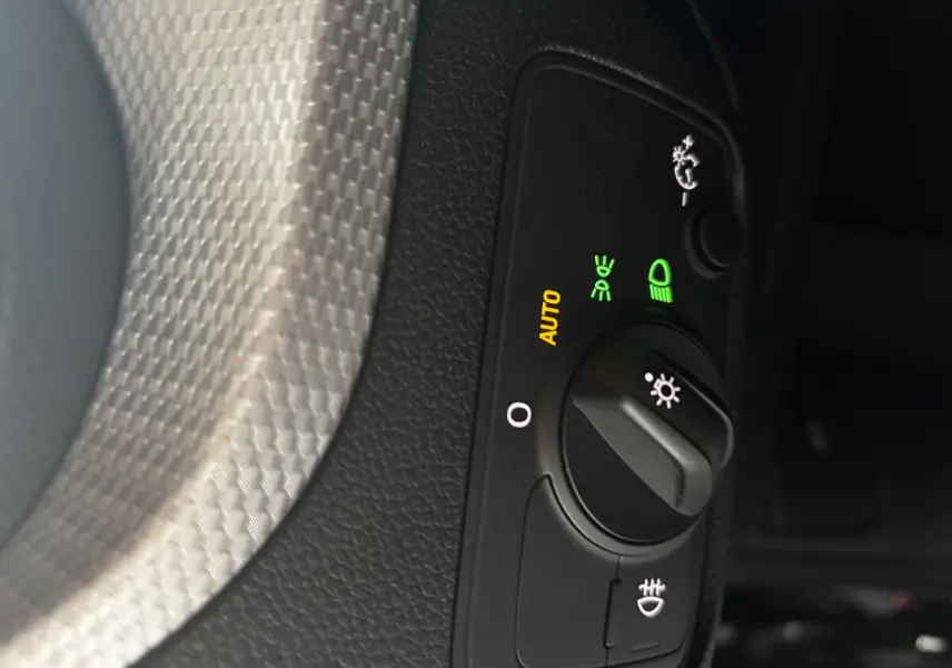 Gros plan sur la commande d’éclairage avec réglage automatique sur Audi Q2 noir 2023, finition S Line.