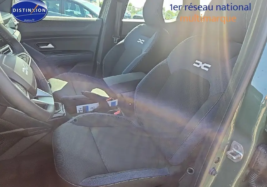 Vue intérieure côté conducteur du Dacia Duster vert kaki 2025, montrant sièges sport avec logo DC et accoudoir central.