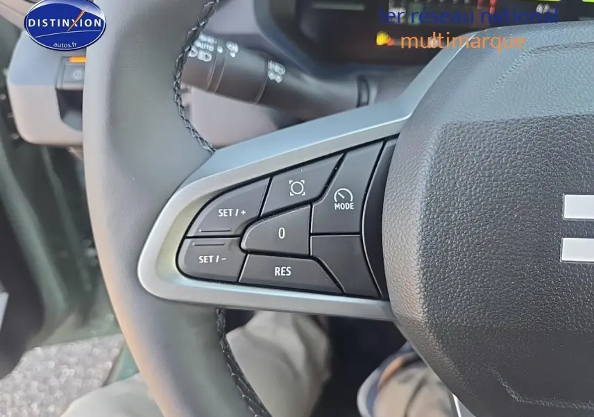 Gros plan sur les commandes au volant côté gauche du Dacia Duster vert kaki 2025, avec boutons multifonctions visibles.