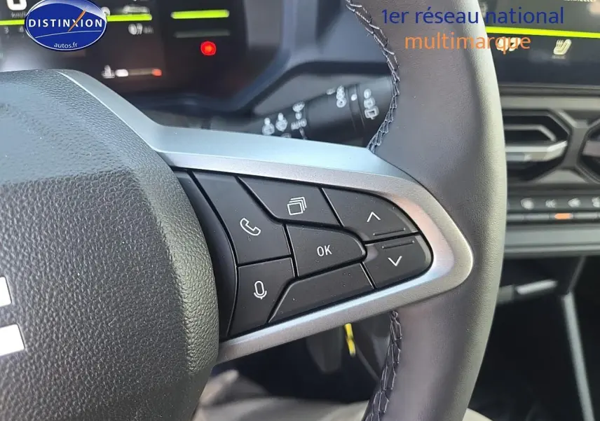 Gros plan sur les commandes multifonctions à droite du volant cuir du Dacia Duster vert kaki 2025, intérieur moderne.
