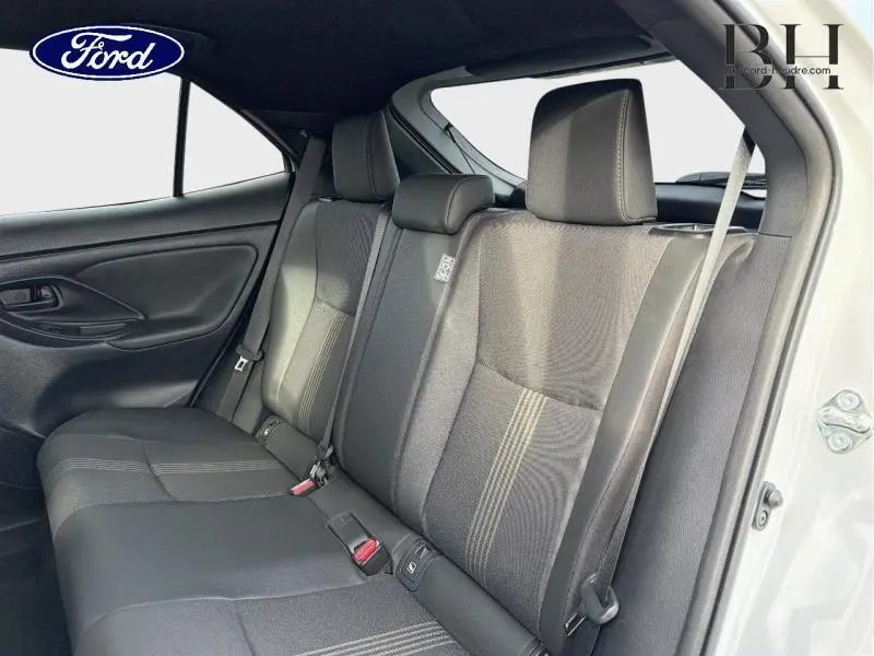 Vue intérieure côté droit sur la banquette arrière noire d'une Toyota Yaris Cross 116h Trail AWD-i blanc lunaire nacré.