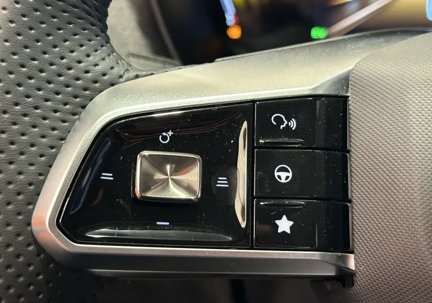 Gros plan sur les commandes multifonctions noires et argent du volant perforé du MG ZS Hybrid+ 2025 en Hampstead Grey.