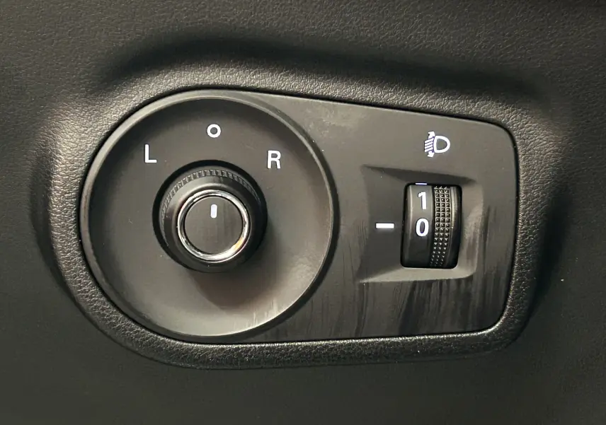 Gros plan sur la commande de réglage des rétroviseurs et de l’intensité des phares du MG ZS Hybrid+ 2025, intérieur noir.
