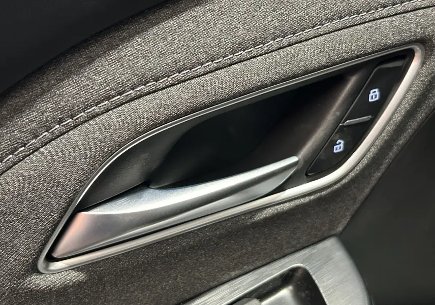 Poignée intérieure de porte côté conducteur du MG ZS Hybrid+ 2025 en tissu gris avec boutons de verrouillage.