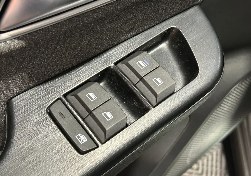 Gros plan sur les commandes électriques des vitres côté conducteur du MG ZS Hybrid+ 2025 en finition Hampstead Grey.