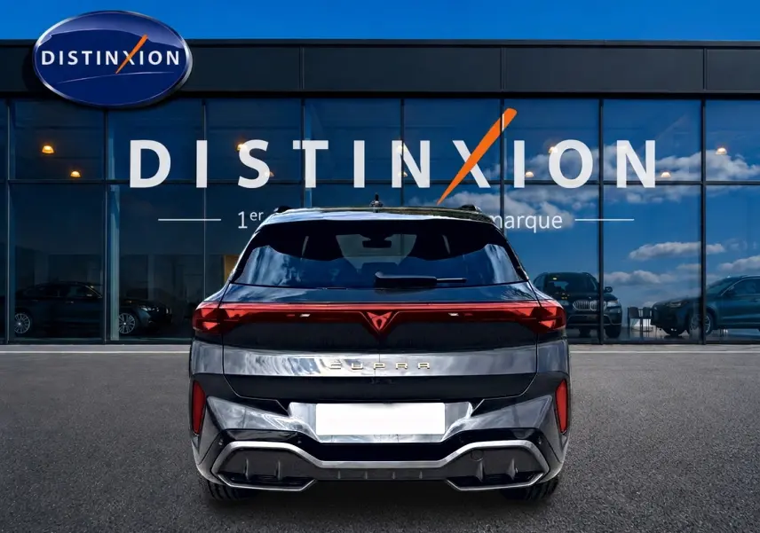 Vue arrière d'un CUPRA TERRAMAR gris timanfaya avec feux LED et logo distinctif rouge, devant un showroom Distinxion.