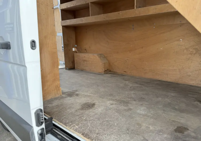Intérieur du Renault Master blanc vu de la porte latérale ouverte, montrant l'espace de chargement en bois.