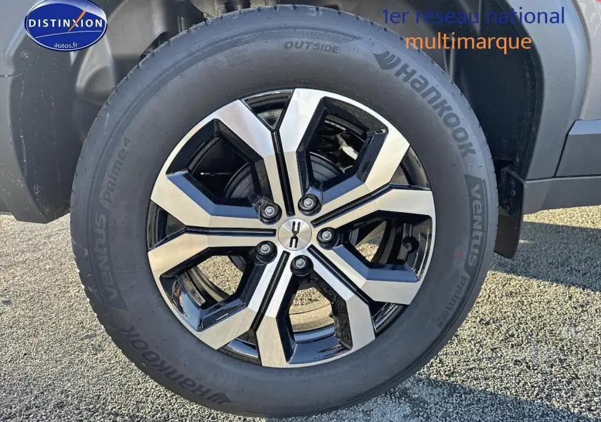 Gros plan sur la roue avant droite du Dacia Duster gris schiste avec jante alu bicolore et pneu Hankook.