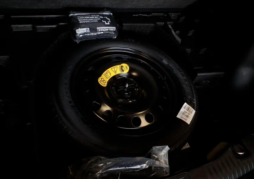 Gros plan sur la roue de secours galette noire dans le coffre du Ford Kuga 2024 Rouge Lucifer.