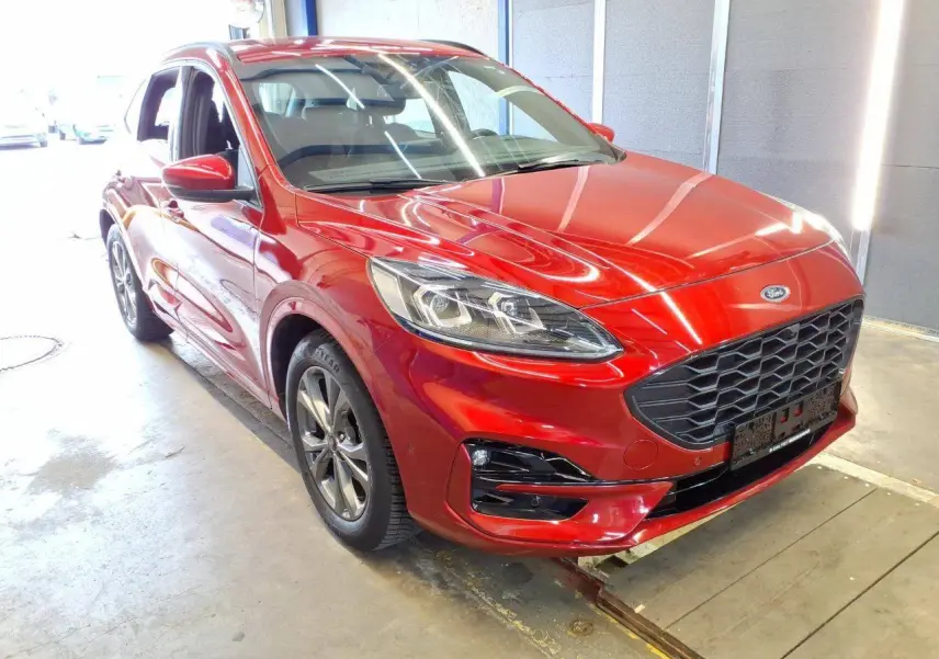 Ford Kuga rouge Lucifer vue 3/4 avant droit, avec calandre noire et jantes alliage 18 pouces en intérieur d'atelier.