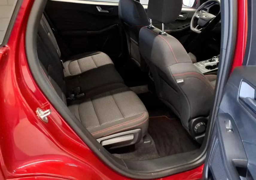 Vue intérieure côté arrière gauche du Ford Kuga rouge Lucifer 2024, sièges tissu noir avec surpiqûres rouges.