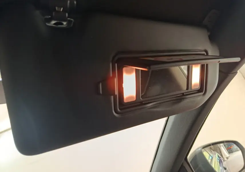 Détail du miroir de courtoisie éclairé sur le pare-soleil côté conducteur intérieur d’un Peugeot 3008 bleu.