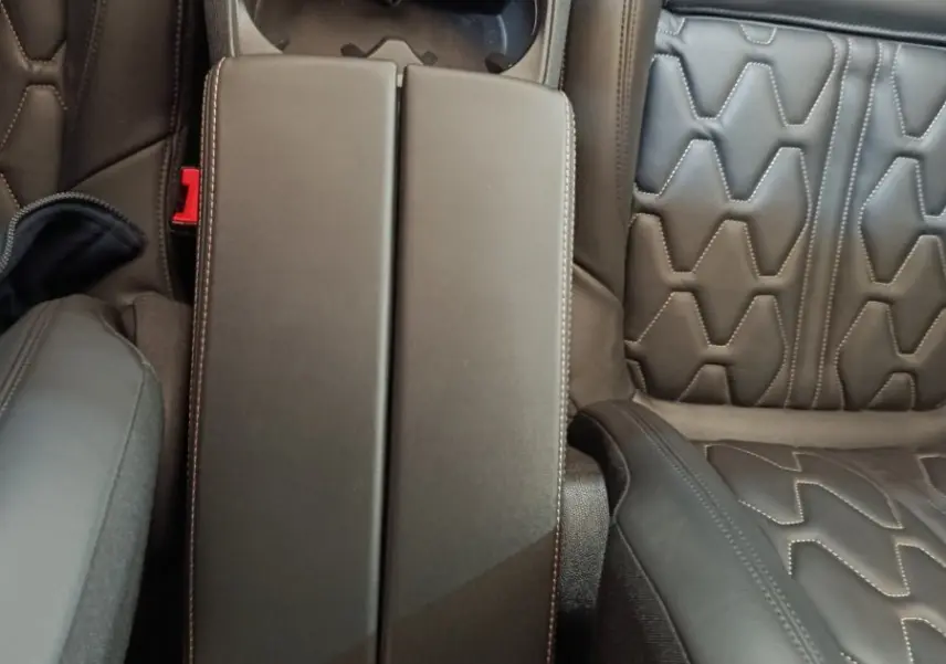 Vue plongeante sur l'accoudoir central et les sièges en cuir noir au motif hexagonal du Peugeot 3008 GT Pack hybride rechargeable.