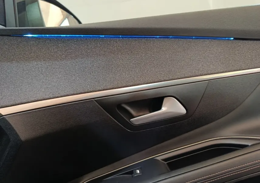 Détail de la porte intérieure côté gauche du Peugeot 3008 bleu, avec éclairage d'ambiance bleu et poignée argentée.