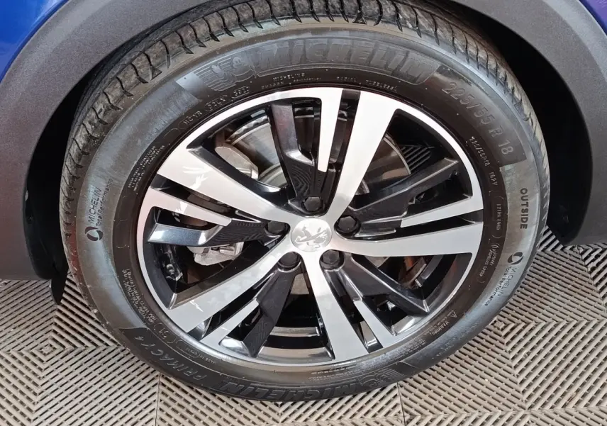 Gros plan sur la roue avant droite du Peugeot 3008 bleu, mettant en valeur la jante alliage bicolore et le pneu Michelin.