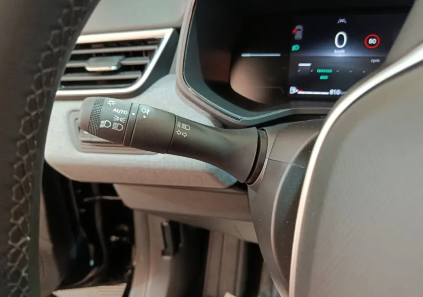 Gros plan sur la manette des phares et clignotants à gauche du volant dans l’habitacle d’une Renault Clio noire 2025.