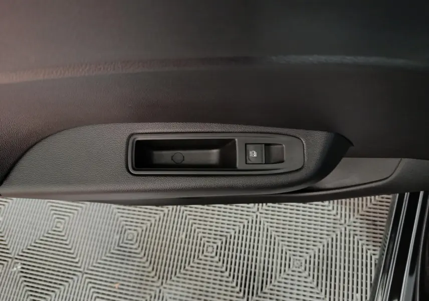 Gros plan sur la commande de lève-vitre côté conducteur de la Renault Clio noire, intérieur sombre.