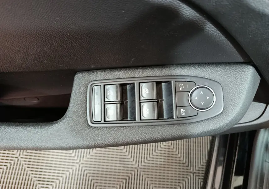 Vue rapprochée des commandes de lève-vitres et réglage des rétroviseurs sur la porte côté conducteur d’une Renault Clio noire.