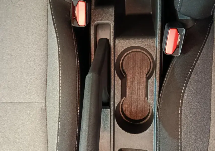Vue plongeante sur la console centrale noire de la Renault Clio Evolution Blue dCi 100 avec frein à main et ceintures rouges.