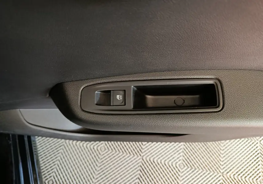 Gros plan sur la commande de lève-vitre électrique côté intérieur d'une Renault Clio noire, finition Evolution Blue dCi 100.