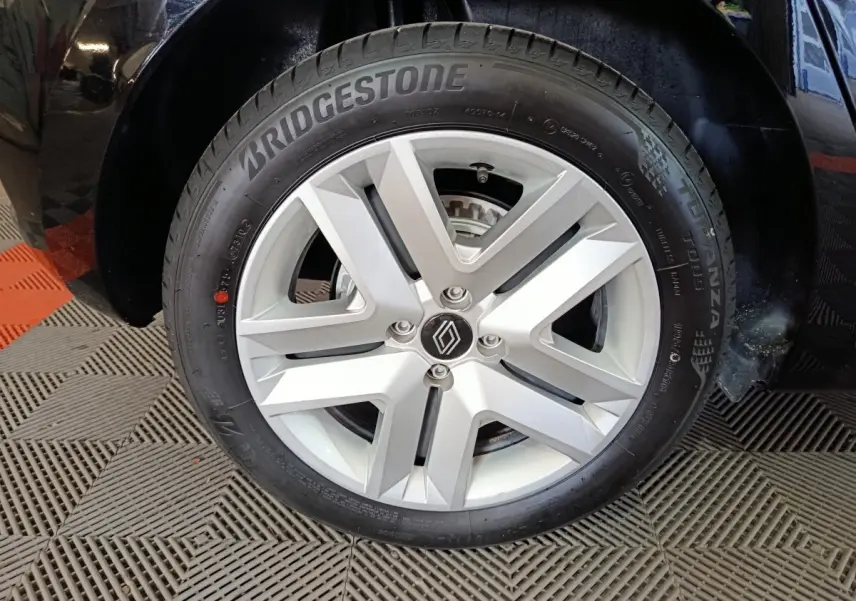 Gros plan sur la roue avant droite d'une Renault Clio noire, avec jante alliage argent et pneu Bridgestone.