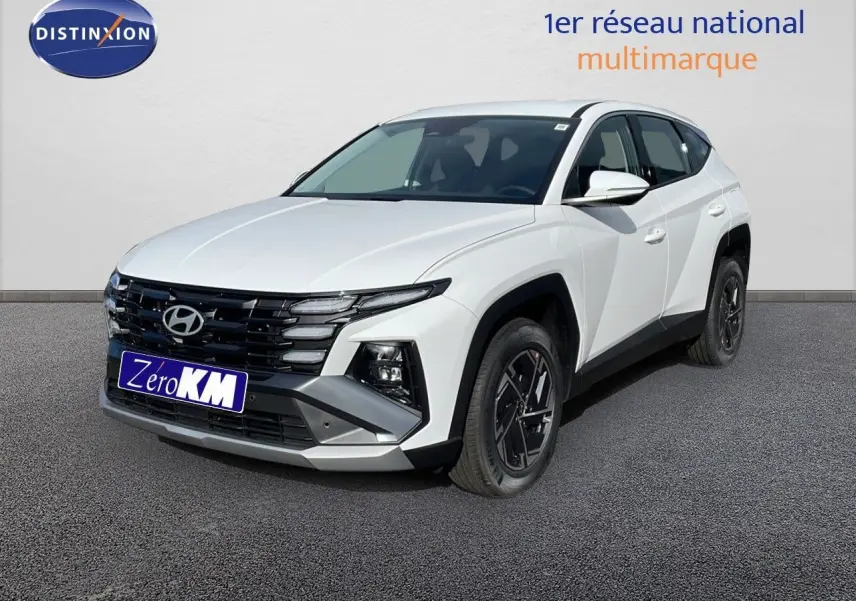 Hyundai Tucson blanc Atlas en 3/4 avant droit, avec calandre noire et jantes alliage noires distinctives.