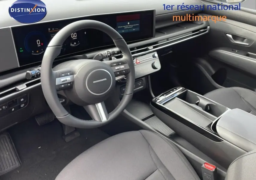 Vue intérieure côté conducteur du Hyundai Tucson 2026, montrant le volant cuir, tableau de bord numérique et console centrale noire.