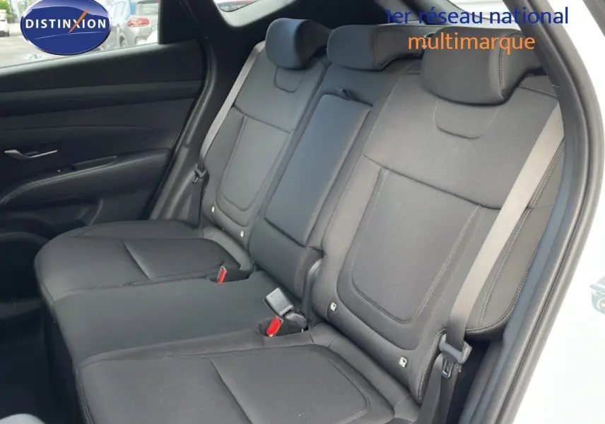 Vue intérieure du siège arrière côté droit du Hyundai Tucson blanc Atlas, montrant les ceintures et les appuie-têtes en tissu noir.
