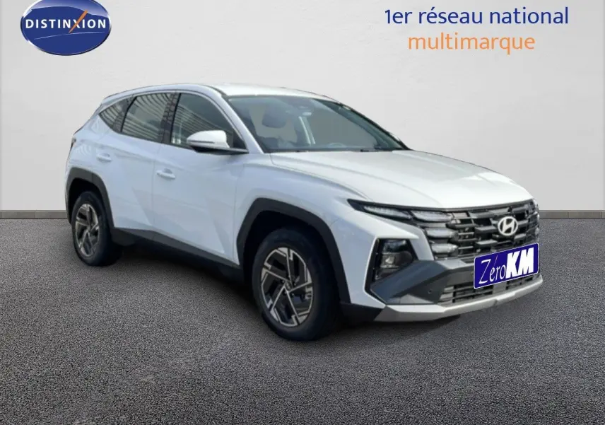 Hyundai Tucson blanc atlas en 3/4 avant droit, SUV hybride avec calandre distinctive et jantes bi-ton.
