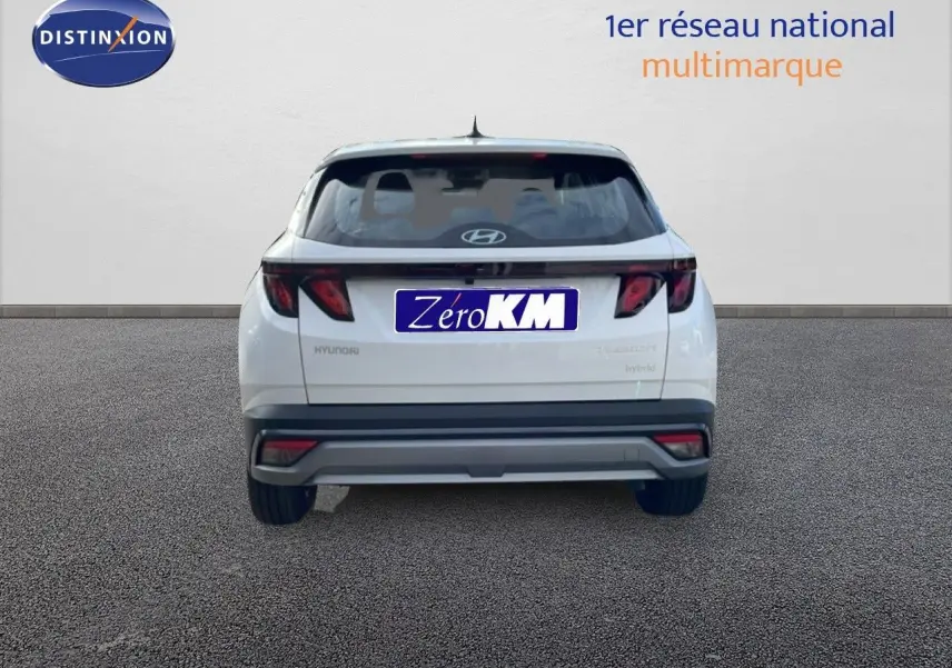 Vue arrière d'un Hyundai Tucson blanc Atlas 2026 hybride essence avec feux arrière sombres et plaque Zéro KM.