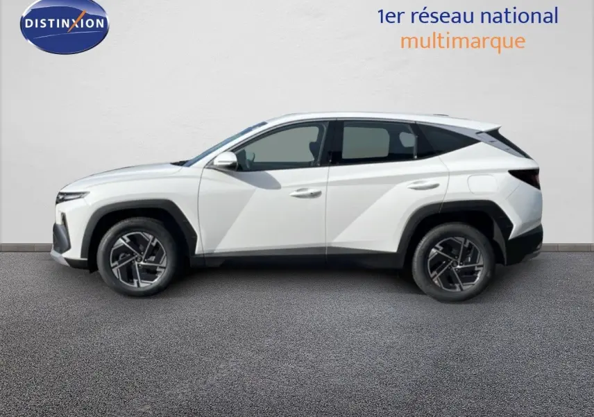 Vue de profil côté gauche d'un Hyundai Tucson blanc Atlas 2026 avec jantes bi-ton et lignes anguleuses marquées.