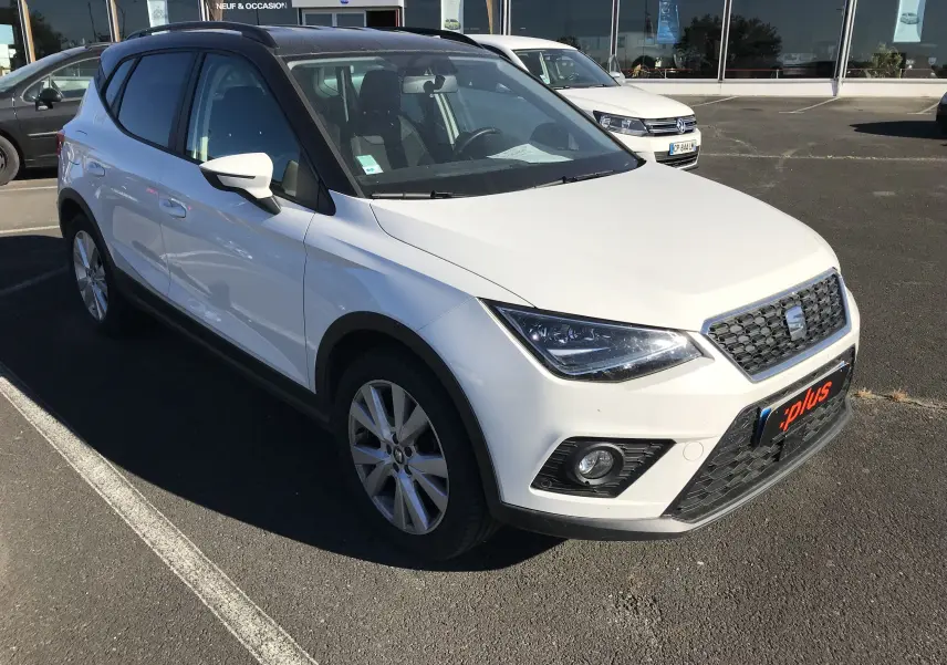 SEAT Arona blanc avec toit noir, vue 3/4 avant droit, mettant en valeur ses phares anguleux et sa calandre noire.