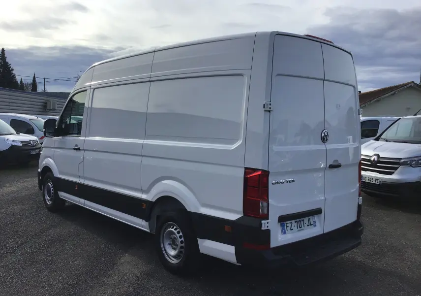 Volkswagen Crafter blanc en vue 3/4 arrière droit, fourgon utilitaire avec portes arrière fermées sur parking.