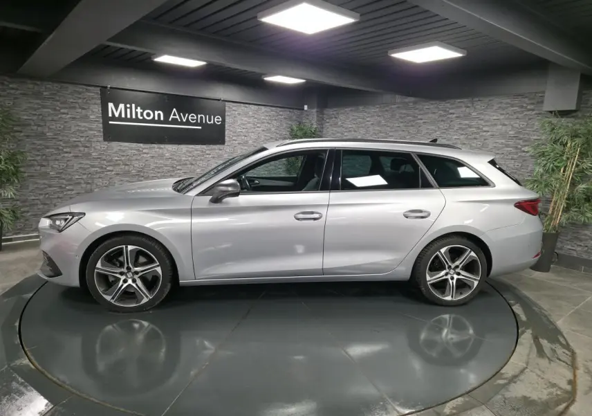 Profil droit d'un break SEAT Leon Sportstourer gris urbain 2022 avec jantes alliage 18 pouces dans un showroom.