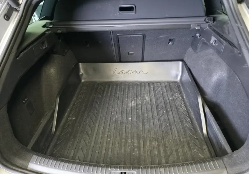 Vue intérieure du coffre spacieux d'un SEAT Leon Sportstourer gris avec tapis de coffre en caoutchouc marqué "Leon".