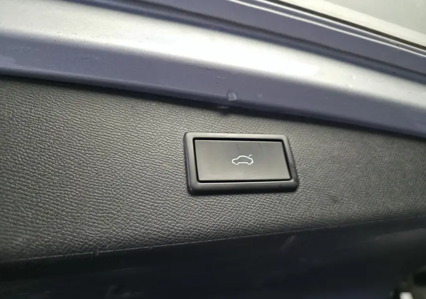 Bouton d'ouverture électrique du hayon sur la garniture intérieure noire du coffre d'un SEAT Leon Sportstourer gris.