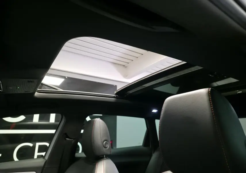 Vue intérieure montrant le toit ouvrant panoramique et les sièges sport en suédine noire avec surpiqûres rouges du SEAT Leon Sportstourer.