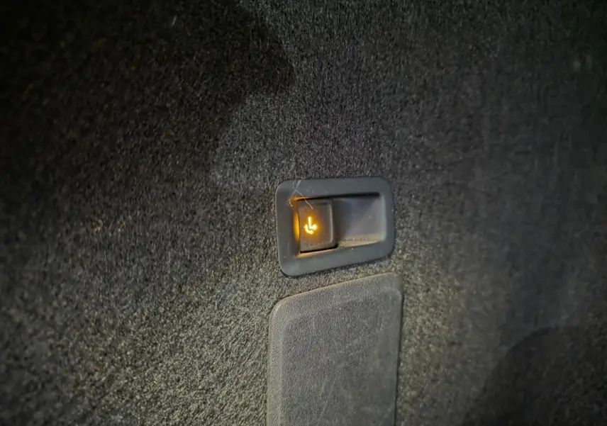 Gros plan sur le bouton d’abattement électrique de la banquette arrière dans le coffre d’un SEAT Leon Sportstourer gris.